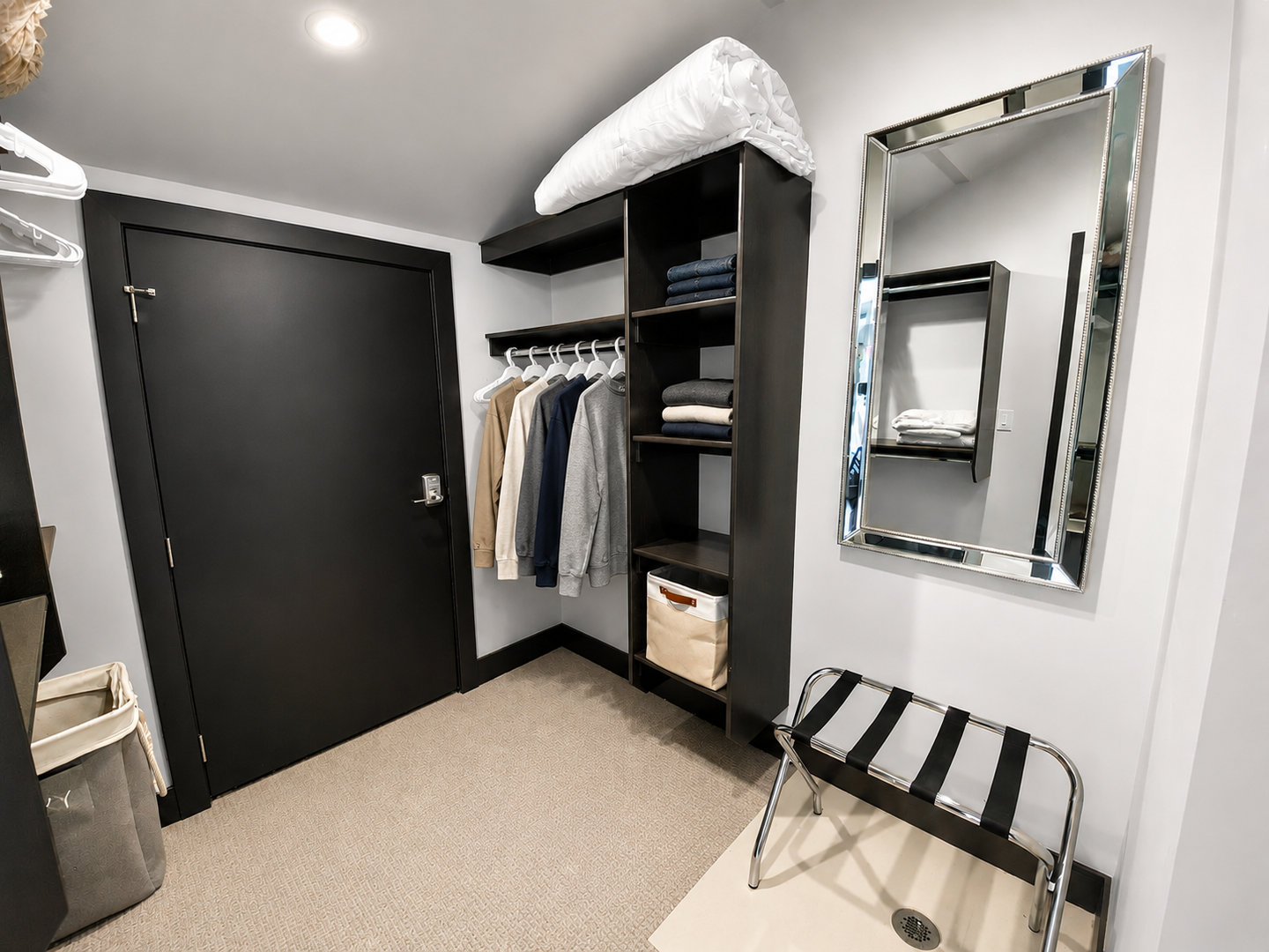 Your spacious walk-in closet features sleek black cabinetry with shelving for folded clothes, hanging space for garments, and a full-length mirror—perfect for getting ready in style.