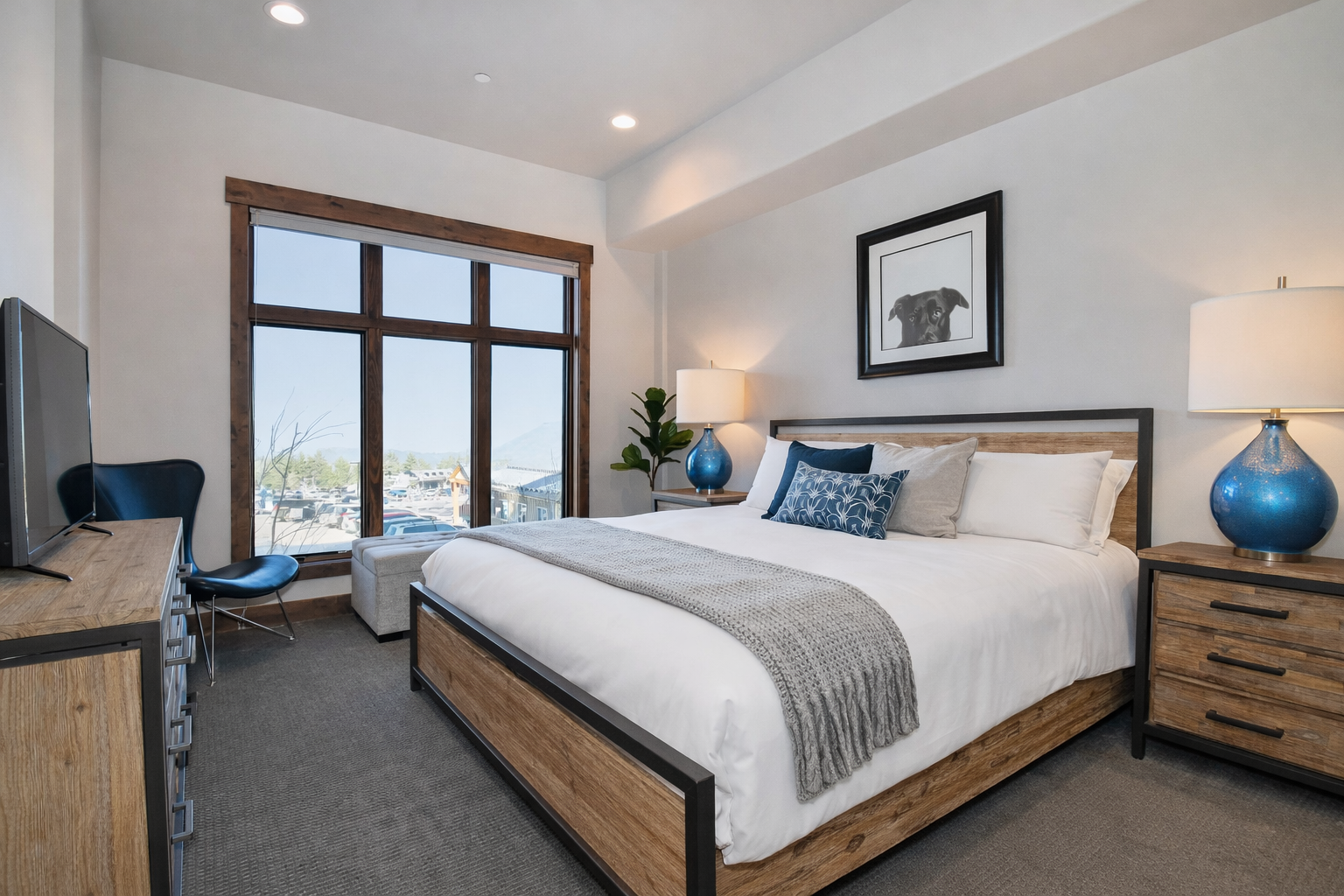 Rest easy in your modern bedroom with crisp linens, soothing blue accents, and city views through oversized windows.