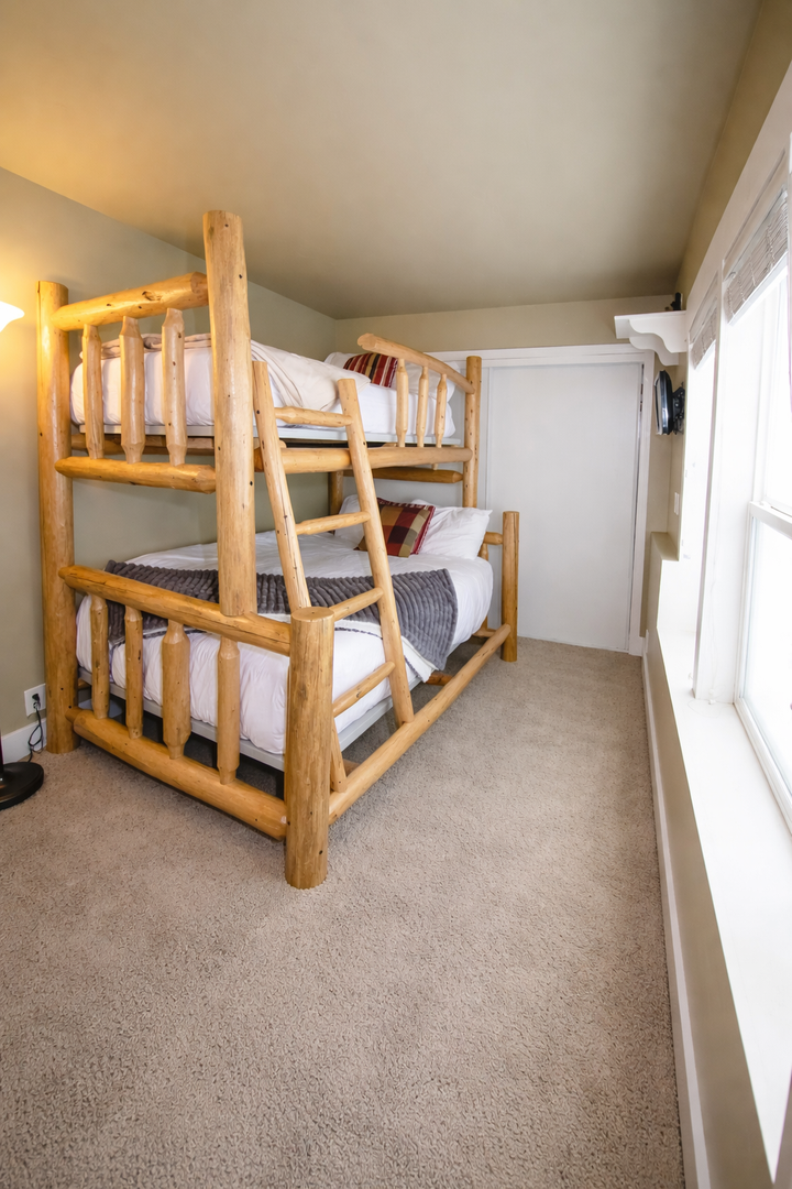 Perfect for families, this bunk room features a sturdy, hand-crafted log bed with a twin over full layout. Bright, natural light and plush carpeting create a cozy, fun retreat.