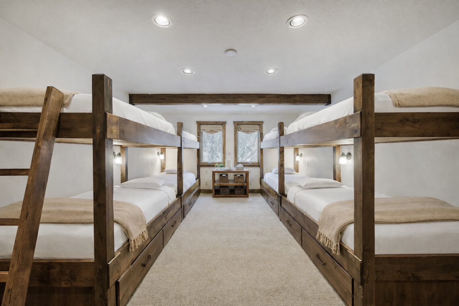 Your group will love this cozy bunk room with rustic wooden beds, soft linens, and individual reading lights for bedtime comfort.