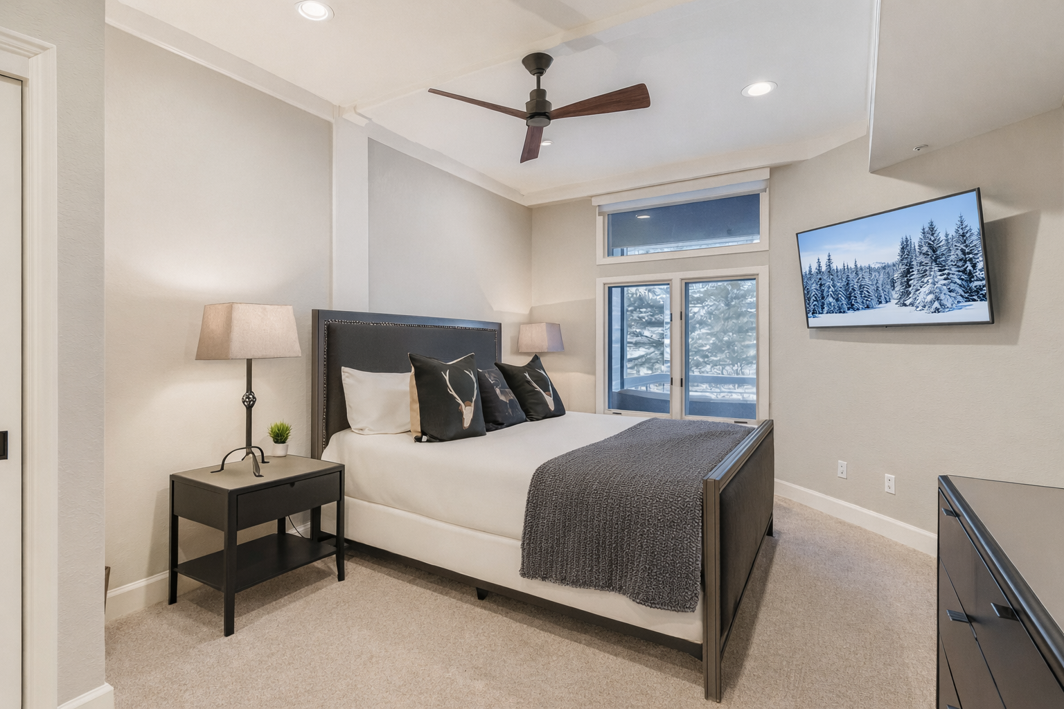 Rest peacefully in your elegant bedroom with comfortable bedding, mountain views, and modern amenities including a ceiling fan and wall-mounted TV.