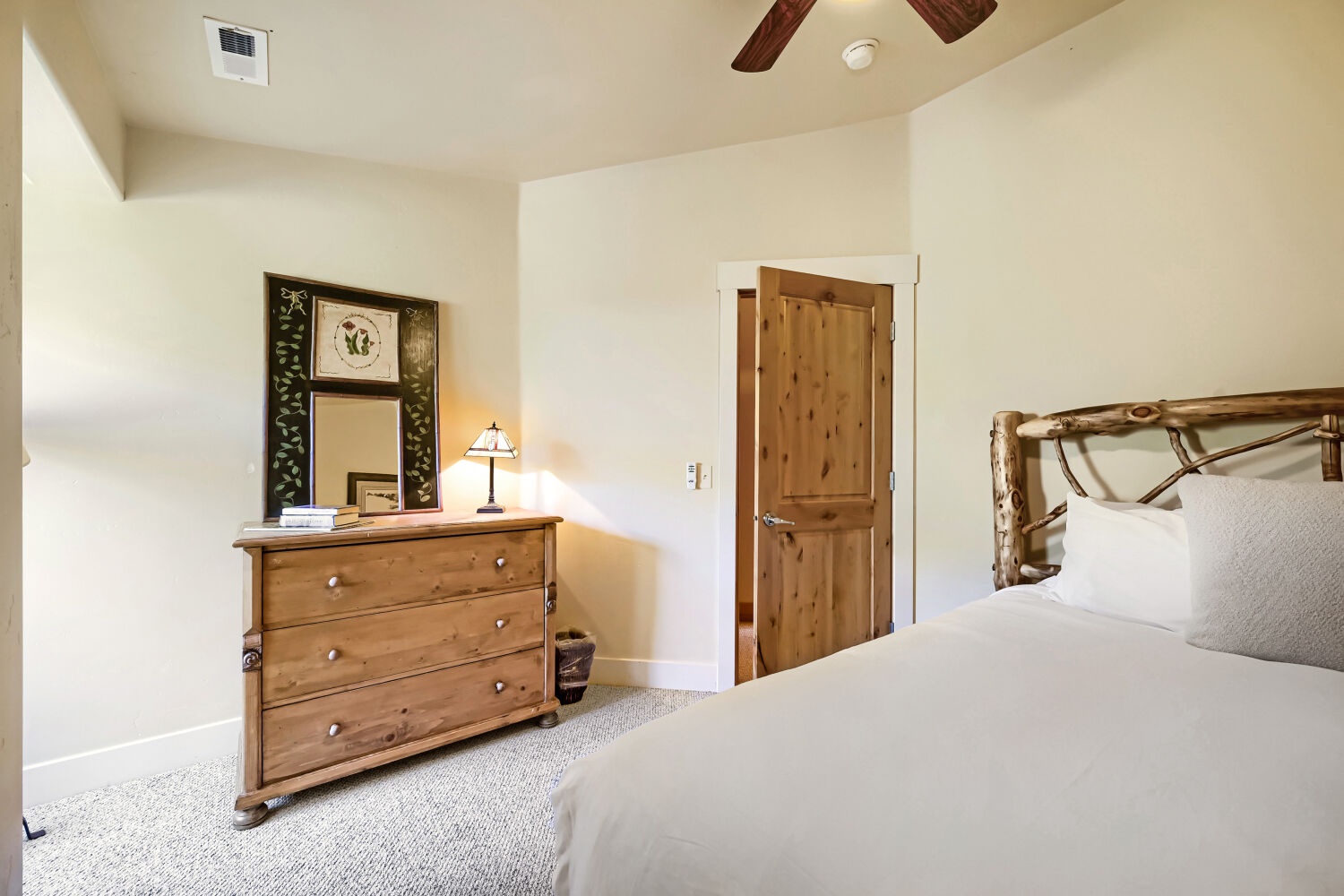 Drift off in this serene bedroom, where rustic wood furniture and a cozy ceiling fan create a peaceful mountain retreat just for you.