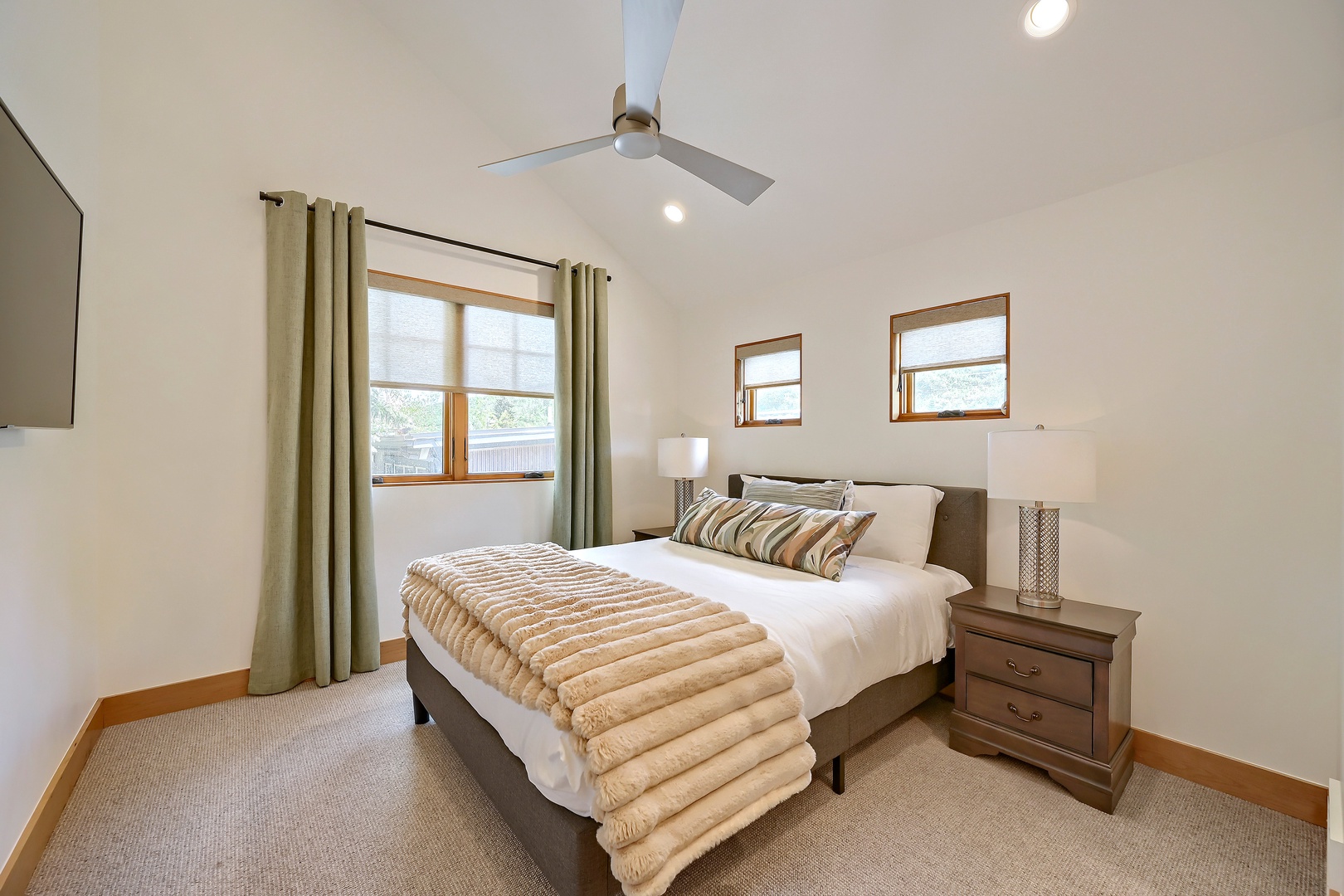 Unwind in this peaceful bedroom with crisp linens, soft lighting, and a gentle ceiling fan. Natural light filters through the windows, creating a serene retreat for your stay.