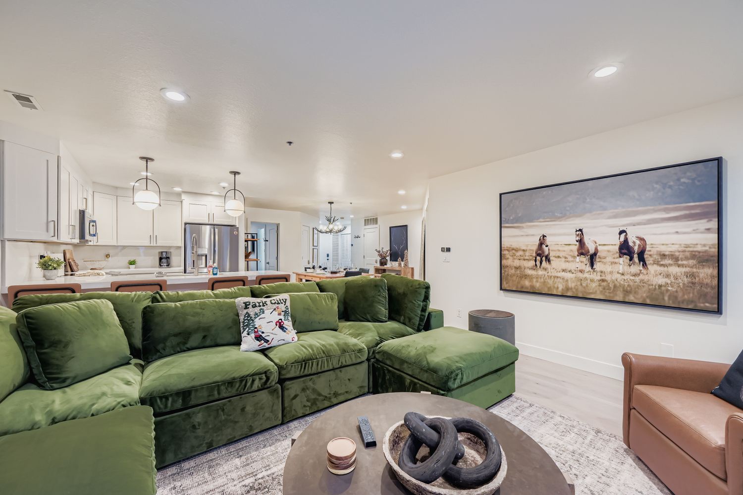 Relax in your spacious open-concept living area with plush green sectional seating and modern kitchen, perfect for unwinding after exploring the area.