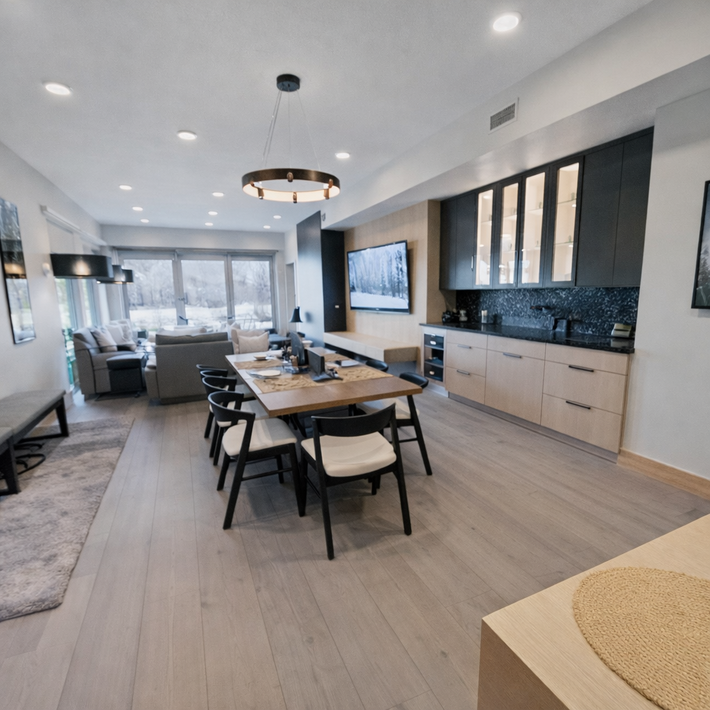 Gather in our open-concept living space, featuring a modern kitchen island with bar seating, a large dining table, and two-tone cabinets.