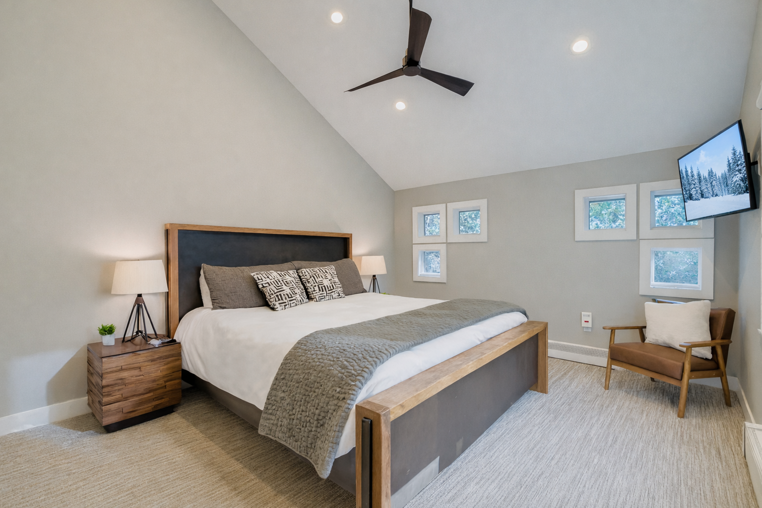 Retreat to the primary suite with a plush king bed, vaulted ceilings, and large windows offering scenic views.