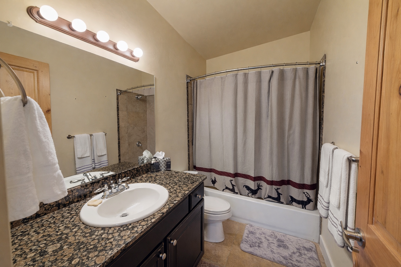 Your spacious bathroom features granite countertops, a relaxing tub-shower combo, and thoughtful wildlife-themed touches that create a cozy mountain retreat atmosphere.