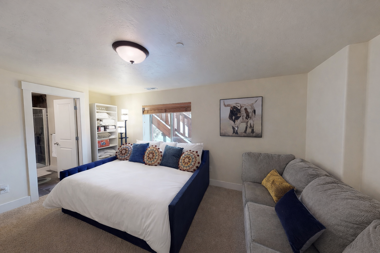 Unwind in your spacious retreat featuring a plush navy bed and cozy gray sofa, perfect for relaxing after exploring the area.