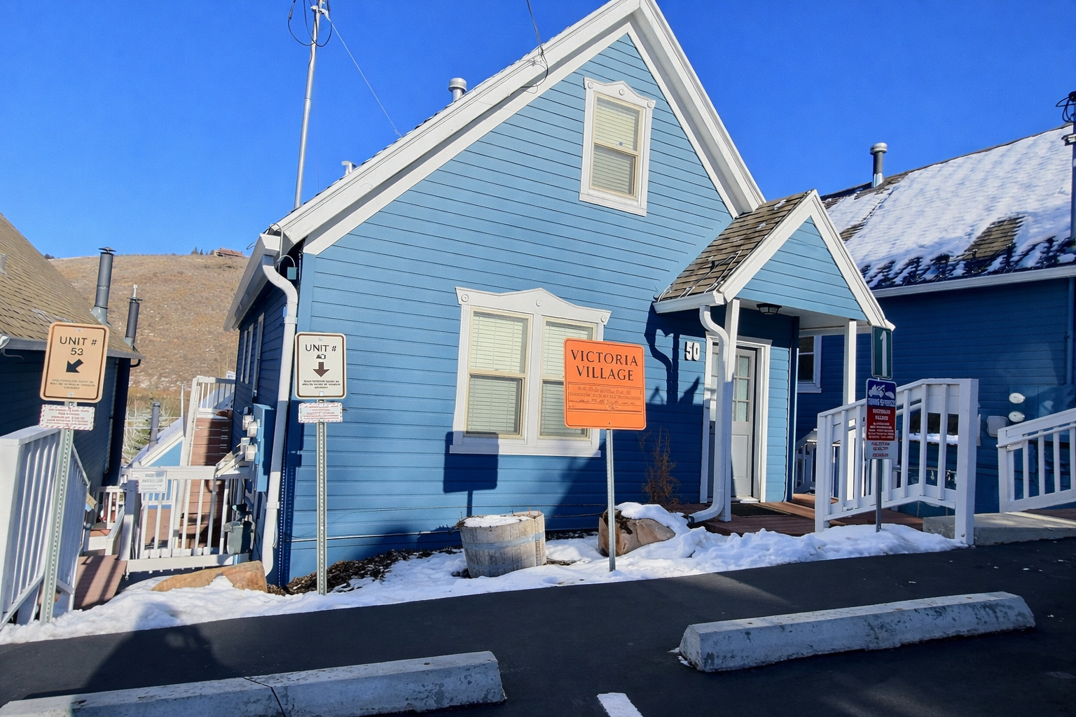 Charming blue cottage-style building with white trim and signage marking the property entrance and units.