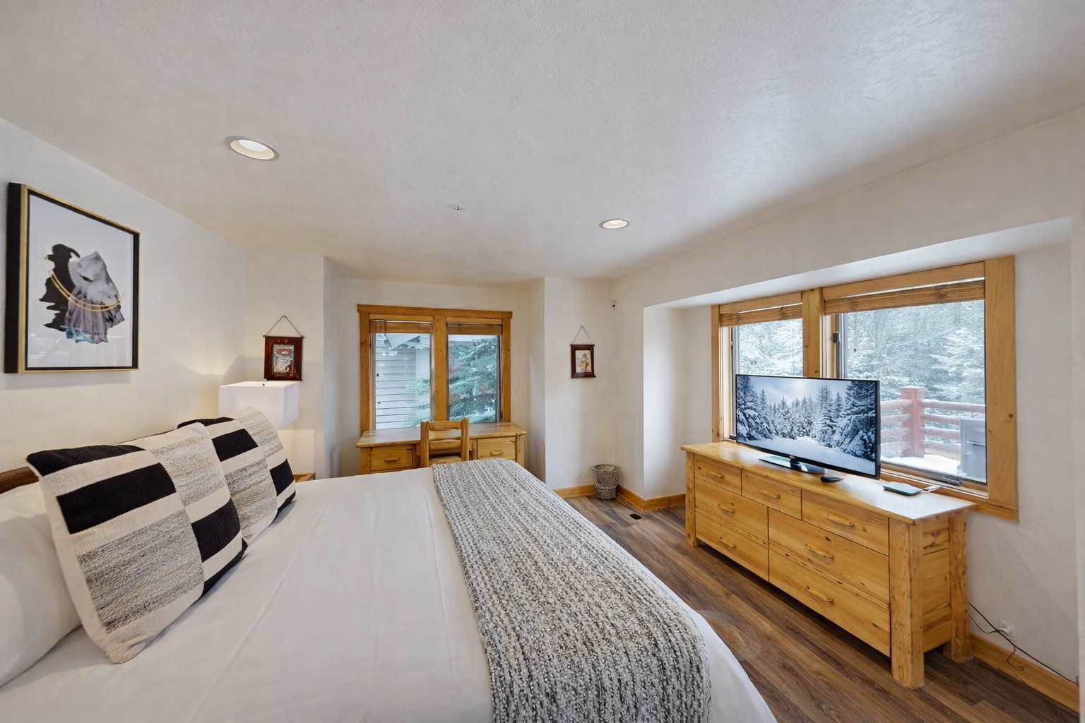 Your cozy bedroom features a plush bed, warm wood accents, and a flat-screen TV for relaxing evenings after mountain adventures.