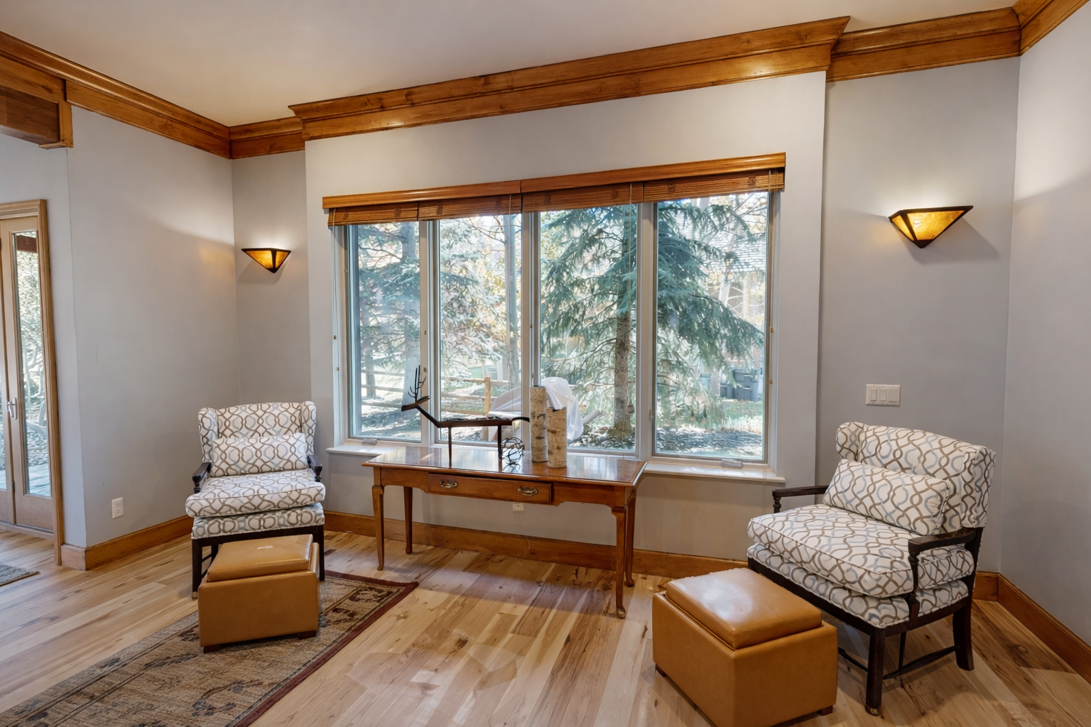 Settle into this bright, cozy reading nook! Enjoy comfortable, patterned armchairs, ottomans, and a rustic console table with tranquil forest views.