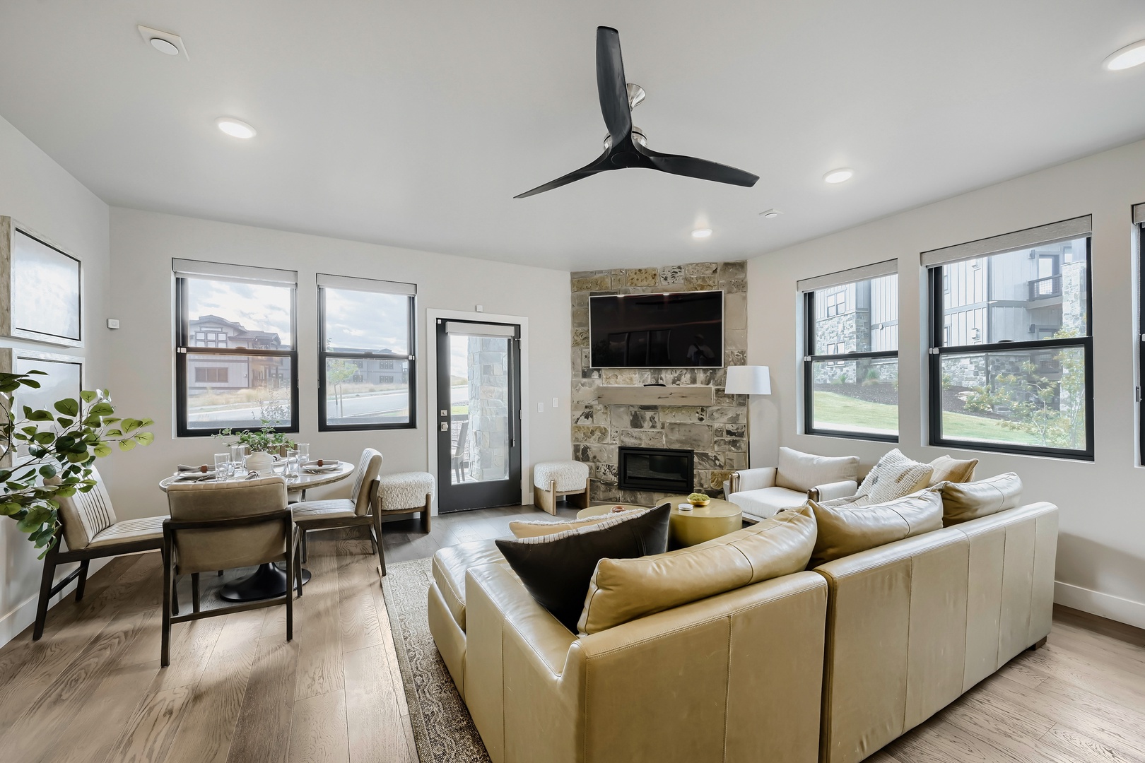 Sink into plush seating beneath vaulted ceilings where natural light pours through multiple windows. The stone fireplace adds warmth while your dining nook awaits memorable meals together.
