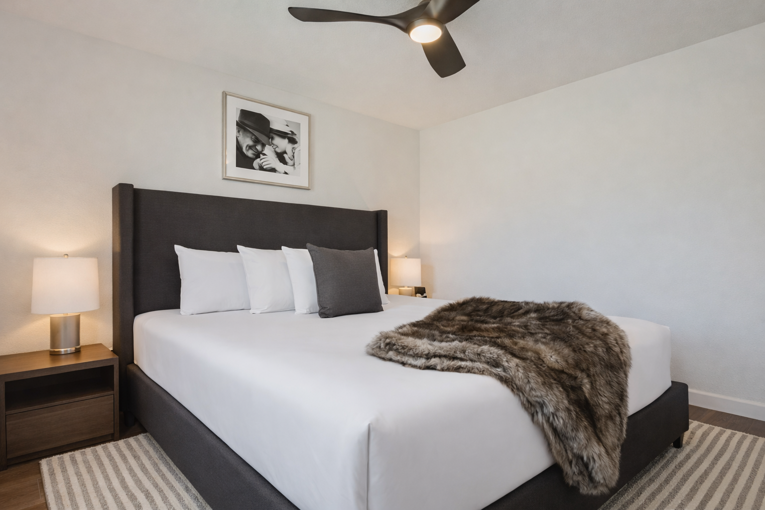 Modern & serene king bedroom with a plush bed, ceiling fan, and large windows. A tranquil space for restful sleep during your getaway.