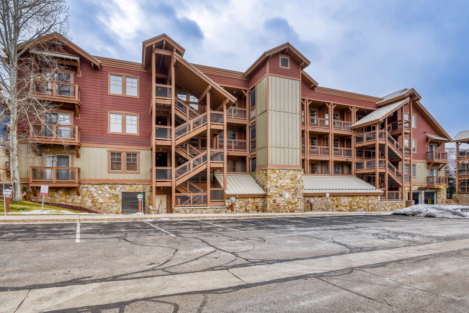 Multi-story vacation rental building featuring rustic wood and stone exterior with mountain lodge architecture and convenient parking access.