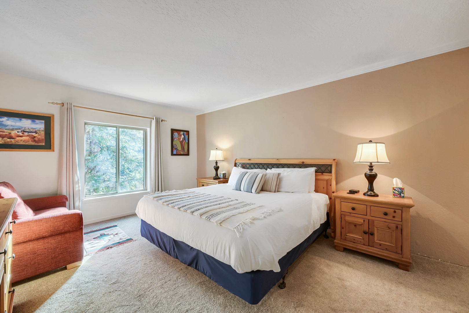 Sink into the plush king bed after a day of adventure, with natural light streaming through the large window and cozy seating just waiting for your morning coffee.