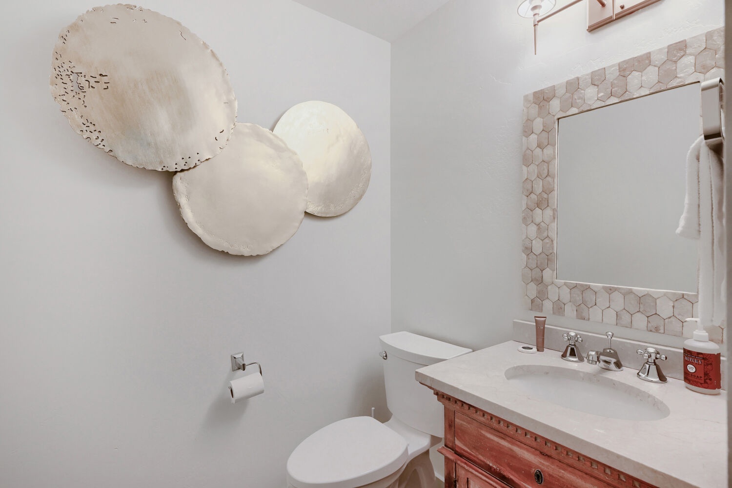 Elegant powder room featuring custom honeycomb tile framing, polished fixtures, and artistic wall decor—your guests will feel pampered from the moment they arrive.