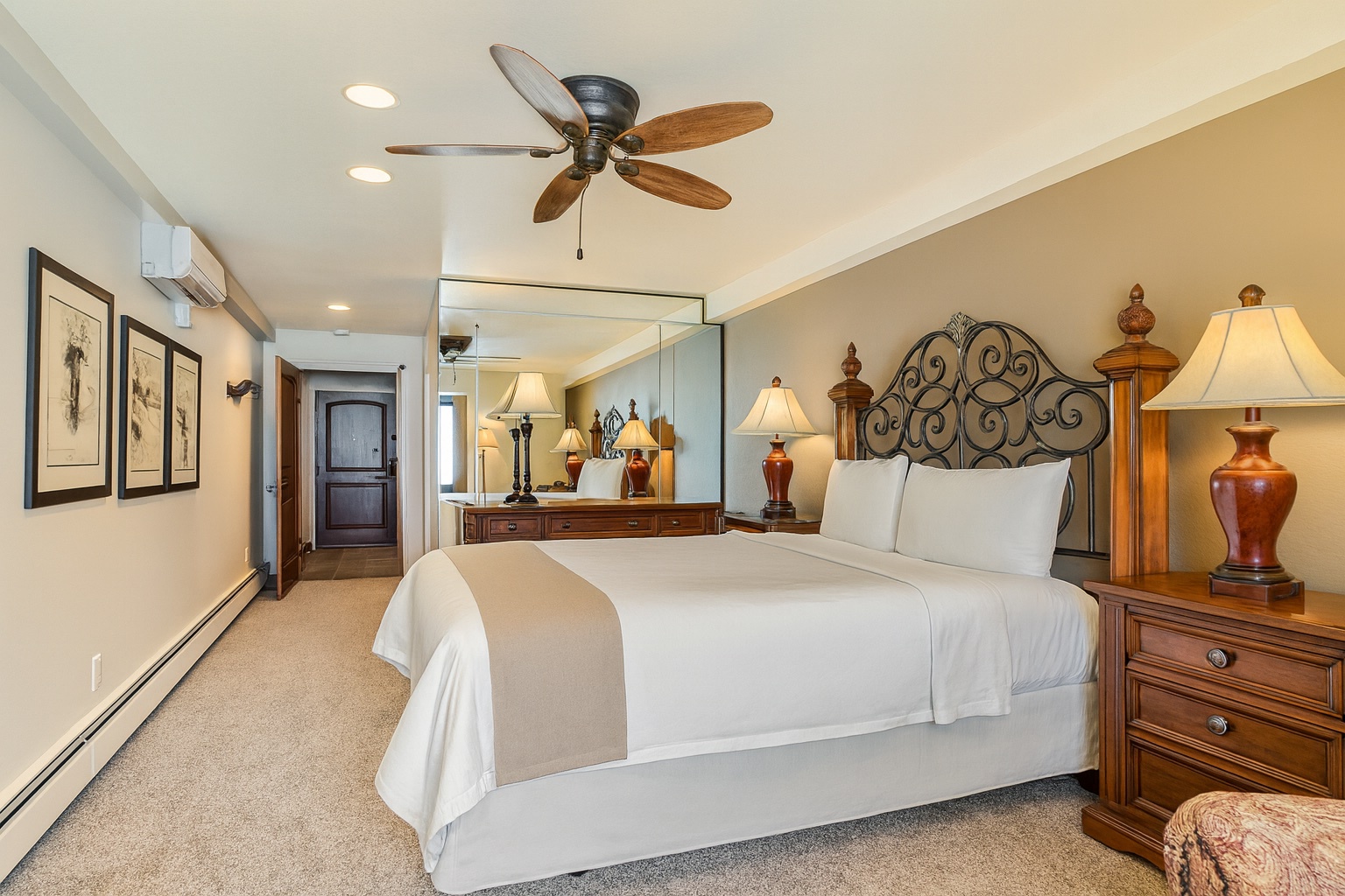 Relax in a bright, inviting bedroom featuring a plush queen bed, elegant wood furnishings, mirrored accents, and warm lighting. Perfect for a peaceful stay after exploring Park City’s skiing, shopping, and mountain adventures.