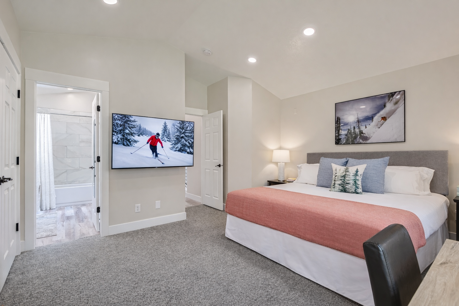 Retreat to the elegant primary bedroom with a plush king-size bed, a large smart TV, and ample natural light.
