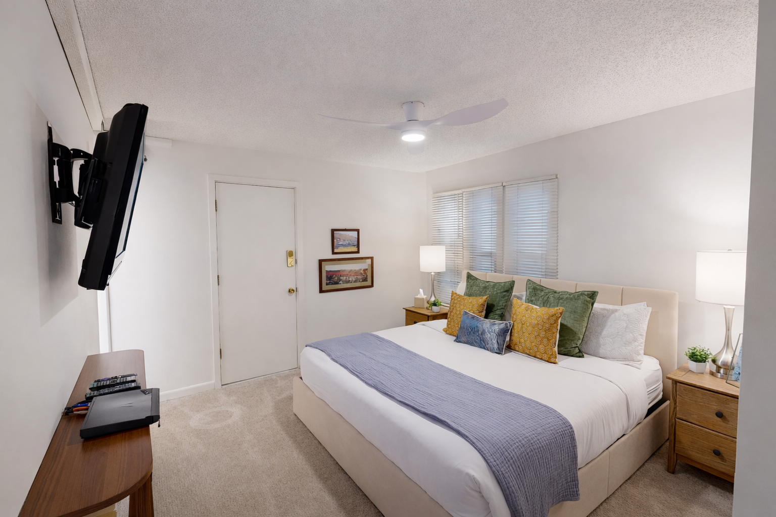 Sink into your comfortable bed with crisp linens and colorful pillows, while enjoying entertainment on the wall-mounted TV in this bright, welcoming bedroom.