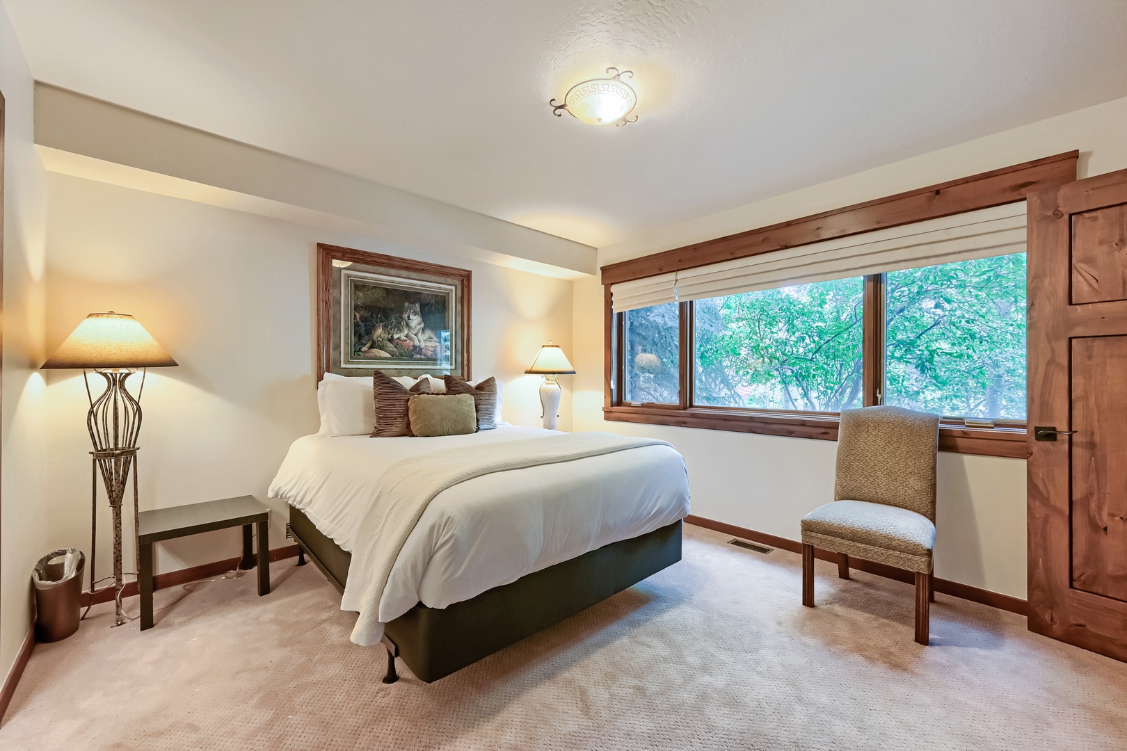 Unwind in your peaceful bedroom where crisp linens and warm wood accents create a restful retreat, while lush greenery outside your window promises quiet, rejuvenating mornings.
