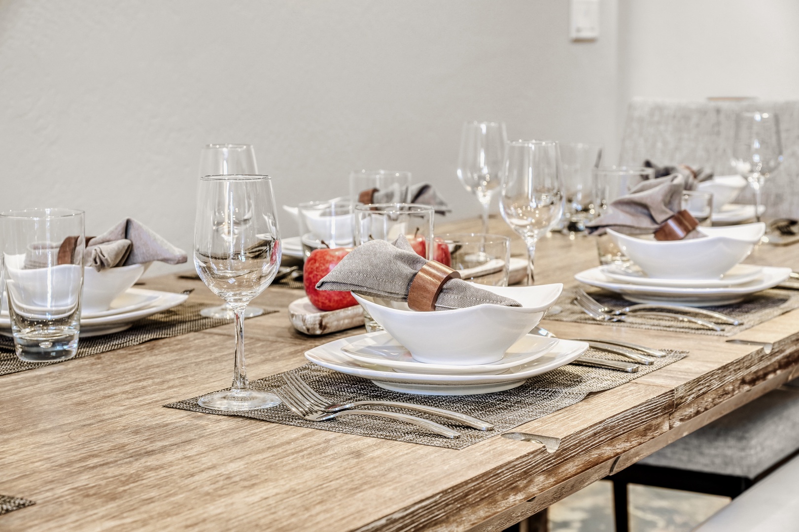 Gather around this beautifully set dining table where elegant place settings and sparkling glassware await your memorable meals together.