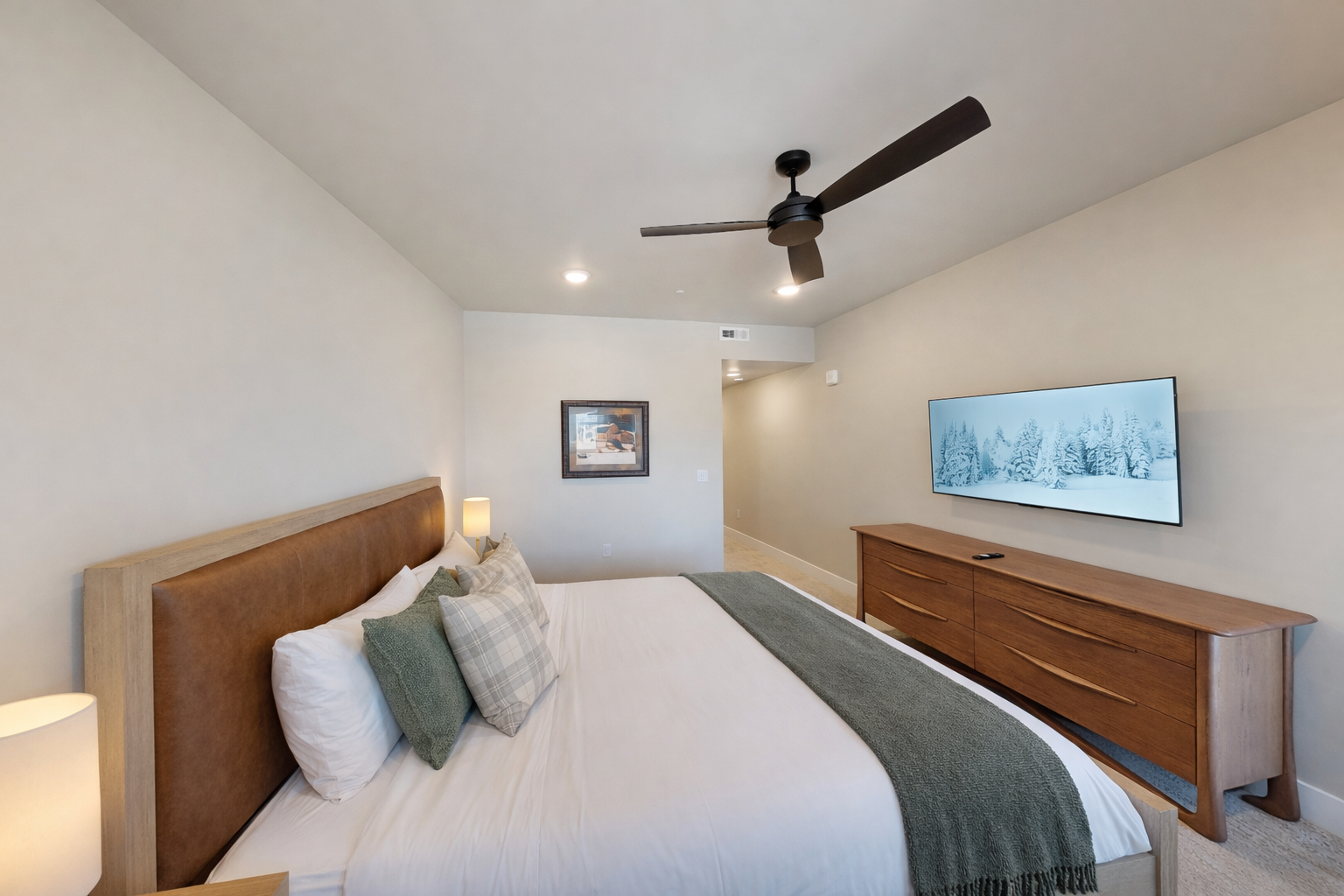 Relax in this bright, modern bedroom featuring a plush king bed and sleek wooden accents. A serene mountain retreat with large windows—perfect for your next Park City adventure.