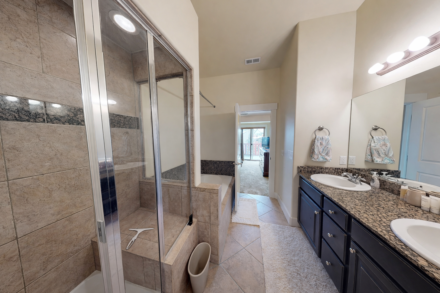 Your luxurious en-suite bathroom features a spacious glass-enclosed shower, elegant granite countertops, and dual vanities for comfort.