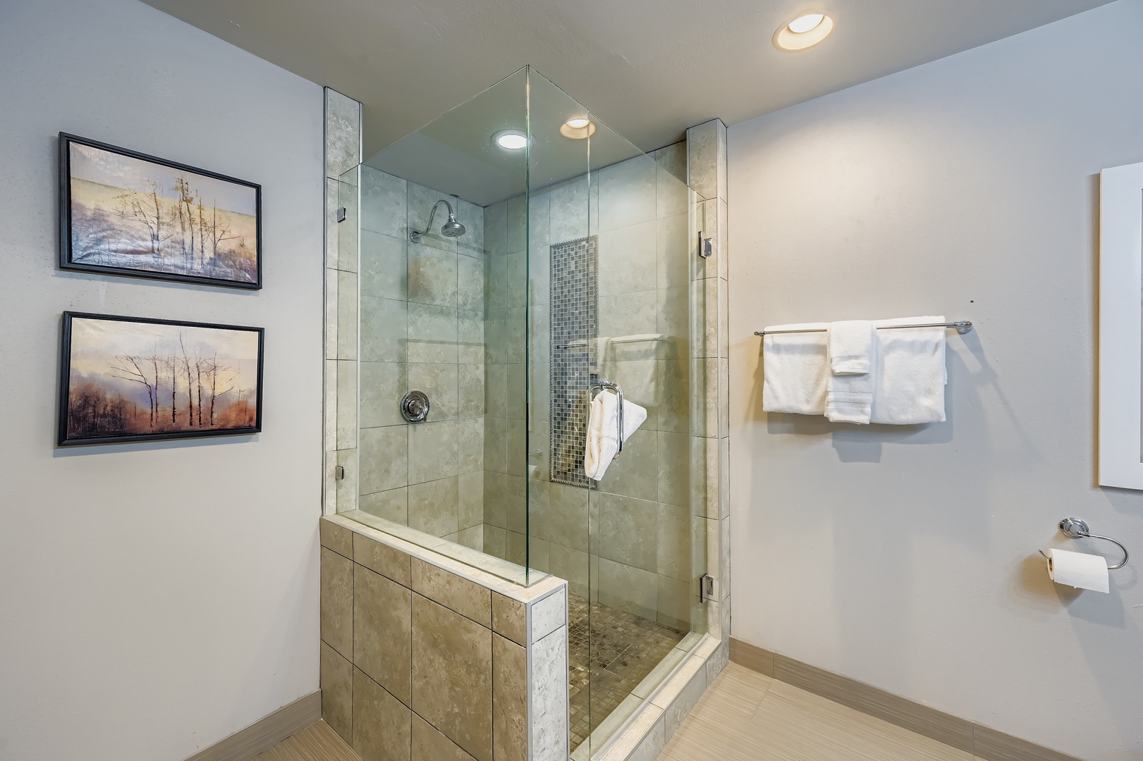Your modern bathroom features a spacious glass-enclosed walk-in shower with rainfall showerhead, towels, and serene artwork creating a spa-like retreat for your mountain getaway.