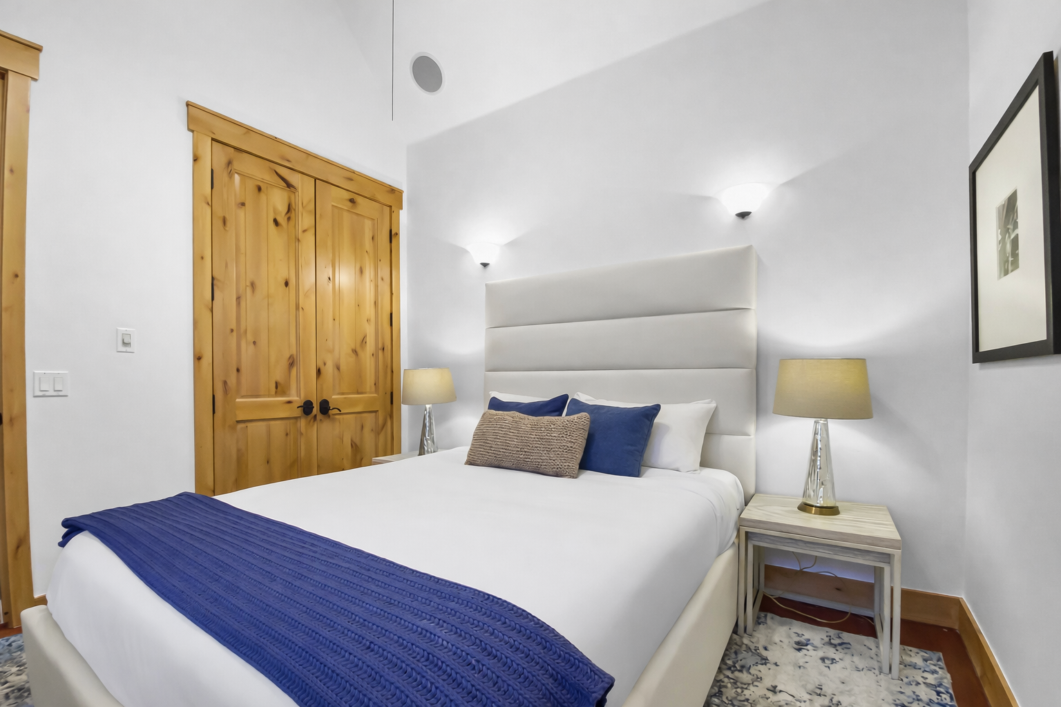 Unwind in your serene bedroom featuring crisp white linens with navy accents, warm wood details, and soft bedside lighting for peaceful nights.