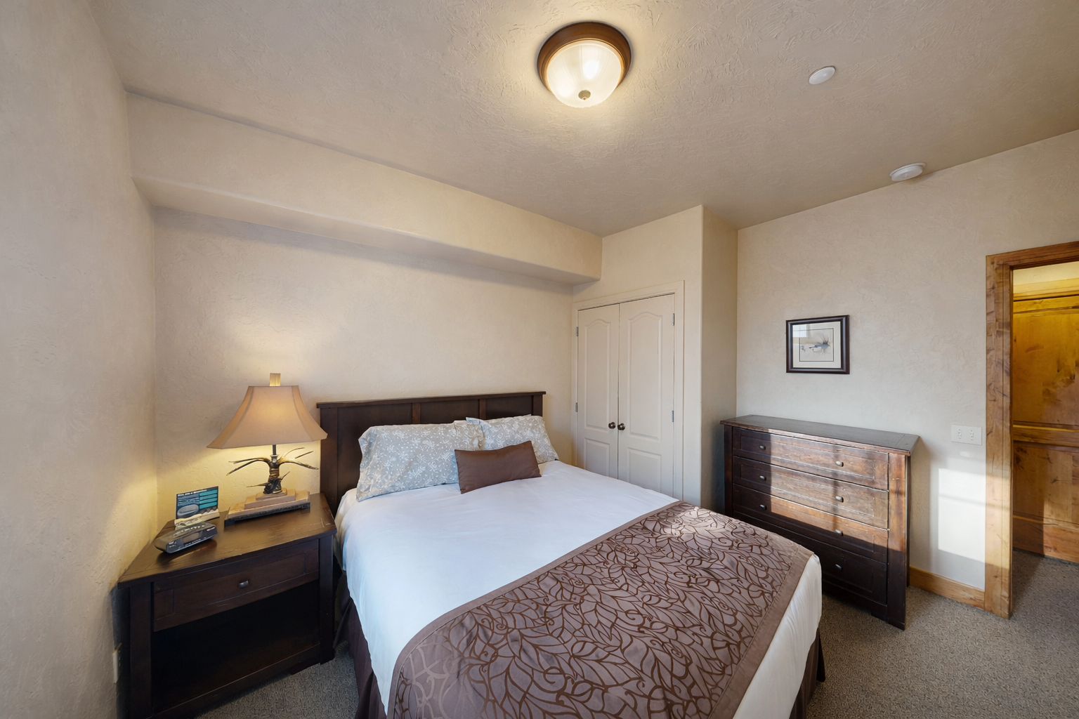 Relax in this cozy bedroom featuring a comfortable queen-size bed, nightstands with lamps, and ample closet/dresser storage space. A quiet retreat for rest and relaxation!