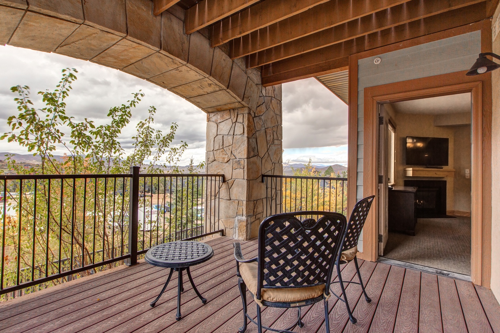 Sip your morning coffee or enjoy an evening drink on the private balcony, featuring comfortable seating, a charming stone facade, and a picturesque view of the surrounding landscape.