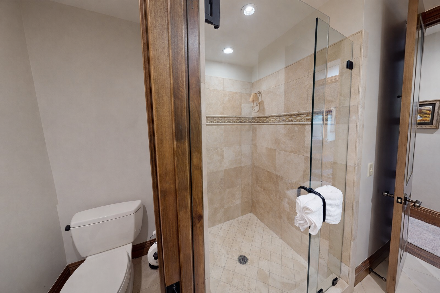 This additional bathroom combines traditional charm with modern utility, featuring a granite-topped vanity, ornate cabinetry, and warm sconce lighting.