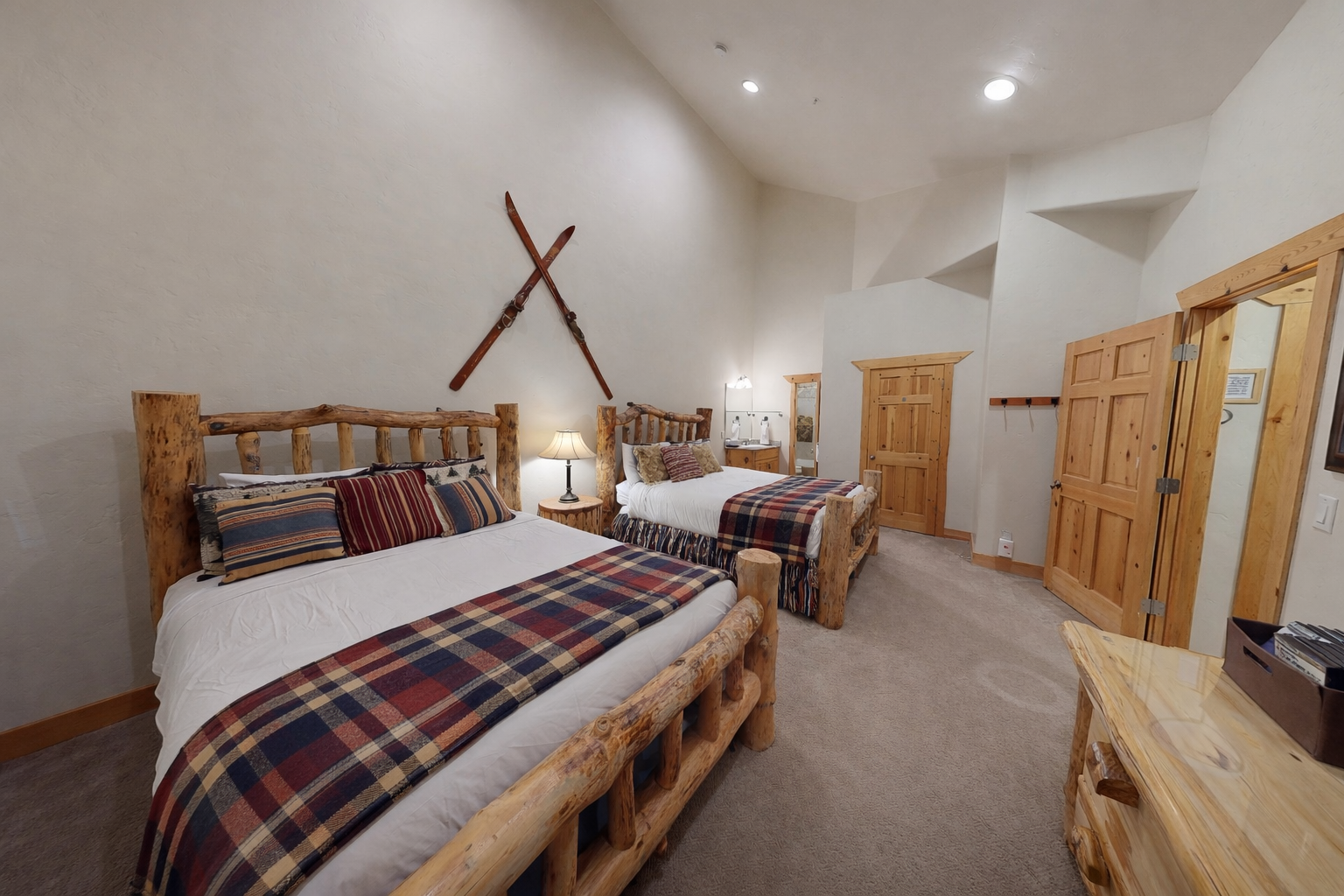 Cozy rustic bedroom with handcrafted log beds, plaid bedding, and ski decor creates your perfect mountain retreat.