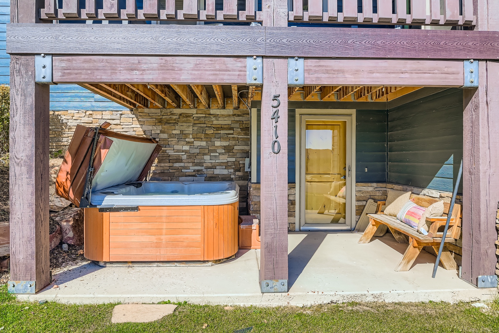 Step onto your private patio where a bubbling hot tub awaits under a wooden pergola. Unwind with beach views, cozy seating, and direct access to your sun-soaked retreat.