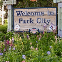 The official Park City welcome sign that greets visitors, surrounded by colorful wildflowers including purple blooms that create a welcoming entrance display.