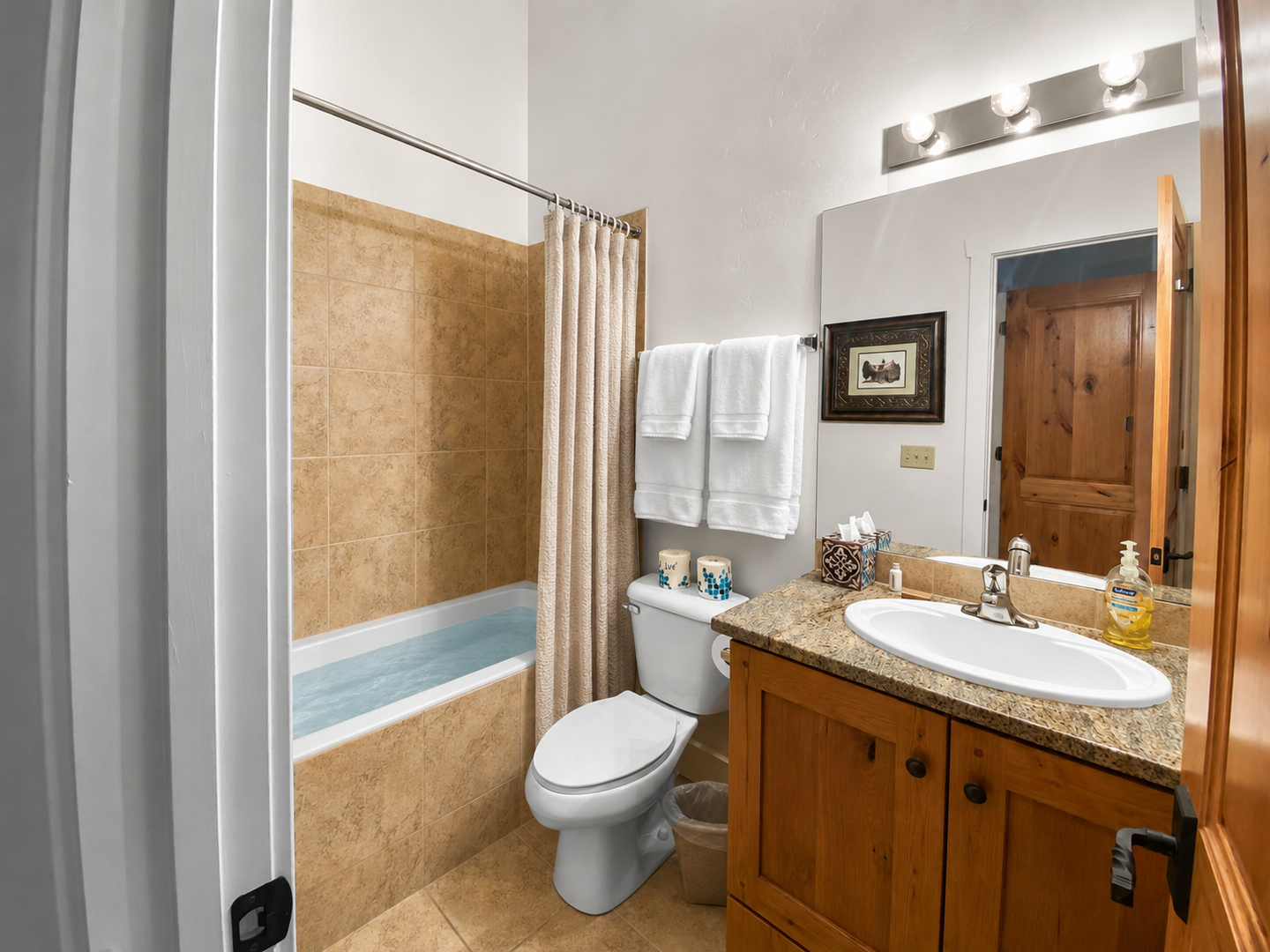 Your private bathroom offers warm travertine tile, plush towels, and thoughtful amenities—everything you need to refresh after a day of mountain adventures.