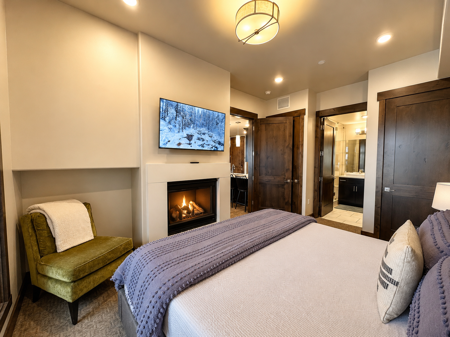 Unwind in this serene primary suite at Blackstone Overlook. This cozy retreat features a private gas fireplace, a wall-mounted Smart TV, and an ensuite bathroom, offering ultimate comfort after a day on the slopes.