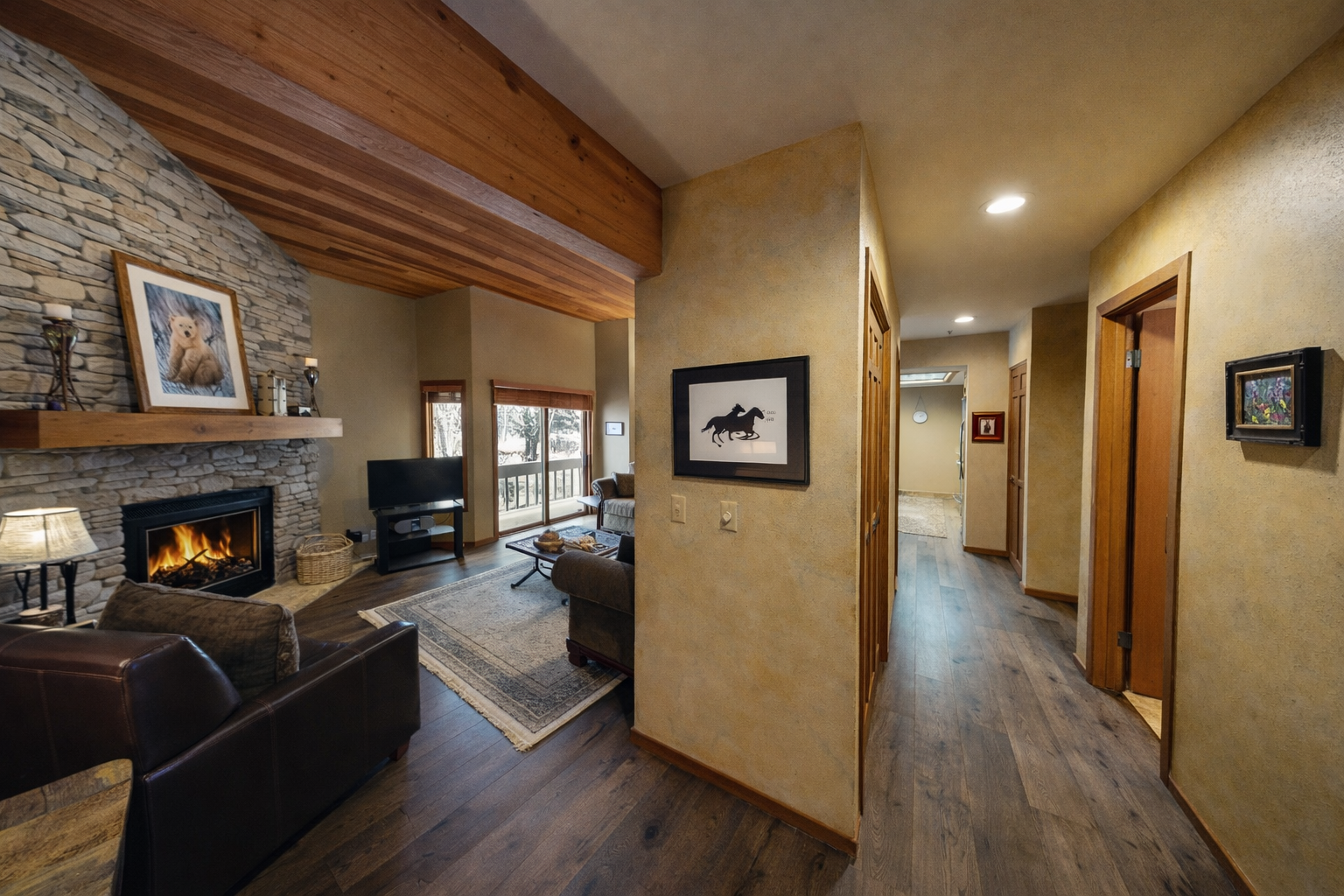 Unwind in your cozy living space with stone fireplace warmth and mountain views through sliding doors.