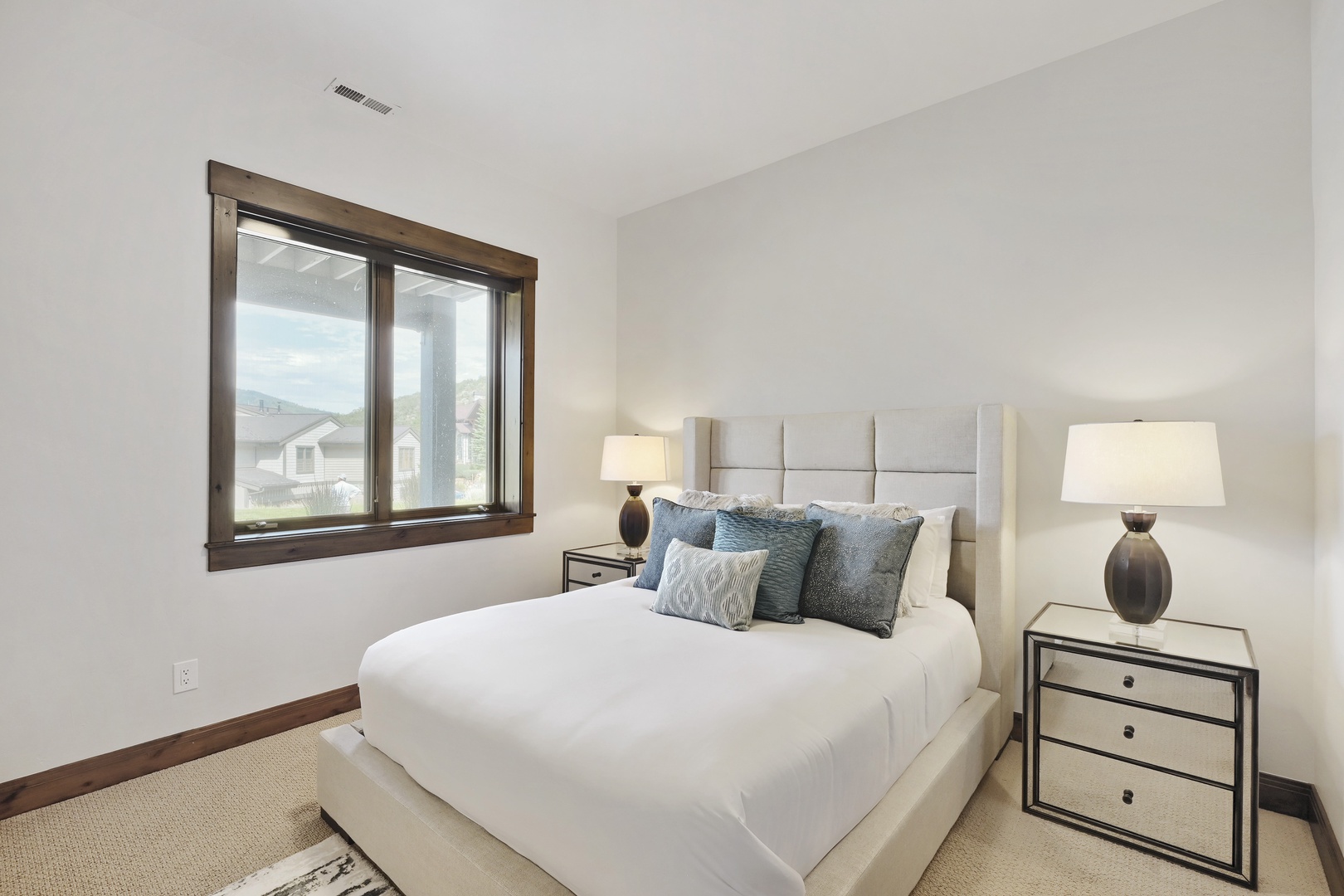 Sink into crisp white linens and plush pillows in your serene bedroom retreat. Wake to natural light and a peaceful neighborhood view through the large window.