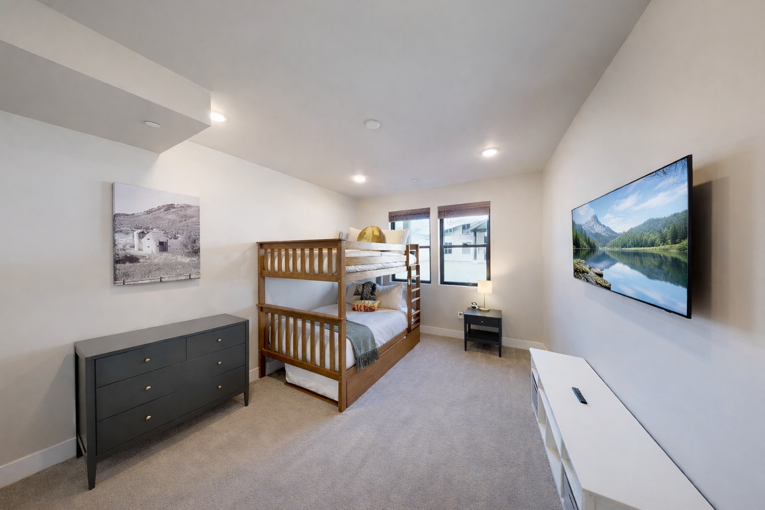 Host large groups in this modern Park City bunk room featuring a triple-tier bed, sleek grey dresser, and bright windows. The perfect year-round family alpine retreat!