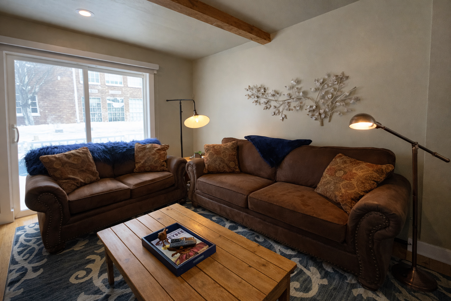 Relax in this cozy mountain retreat featuring a warm fireplace, rustic wooden accents, and plush seating. Enjoy modern amenities like a wall-mounted TV and large windows with bright, natural light.