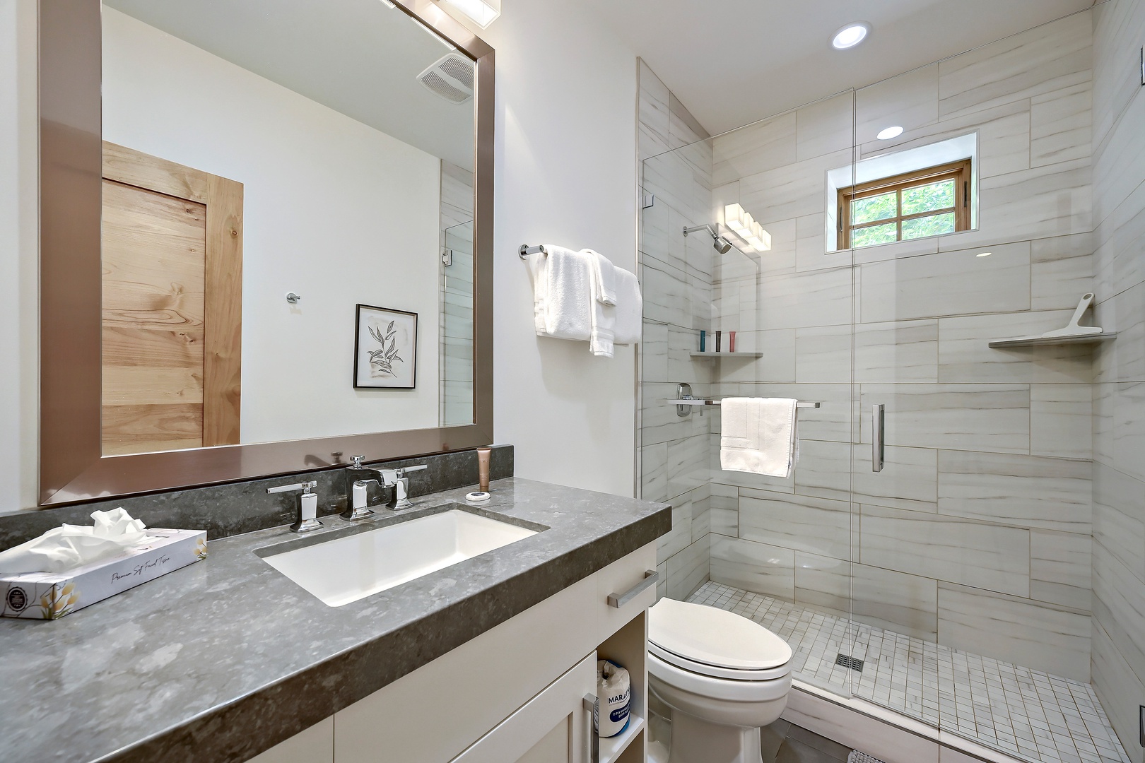 Step into your private spa-like retreat with sleek marble countertops, a walk-in glass shower, and crisp white towels awaiting your arrival.