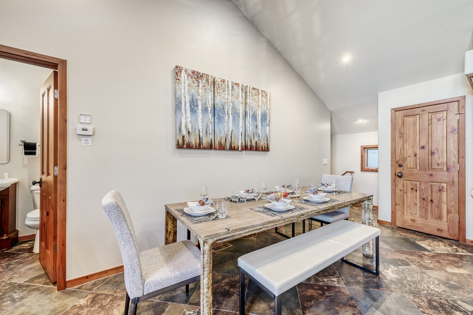 Your dining space features rustic charm with a beautiful wooden table set for memorable meals with loved ones.