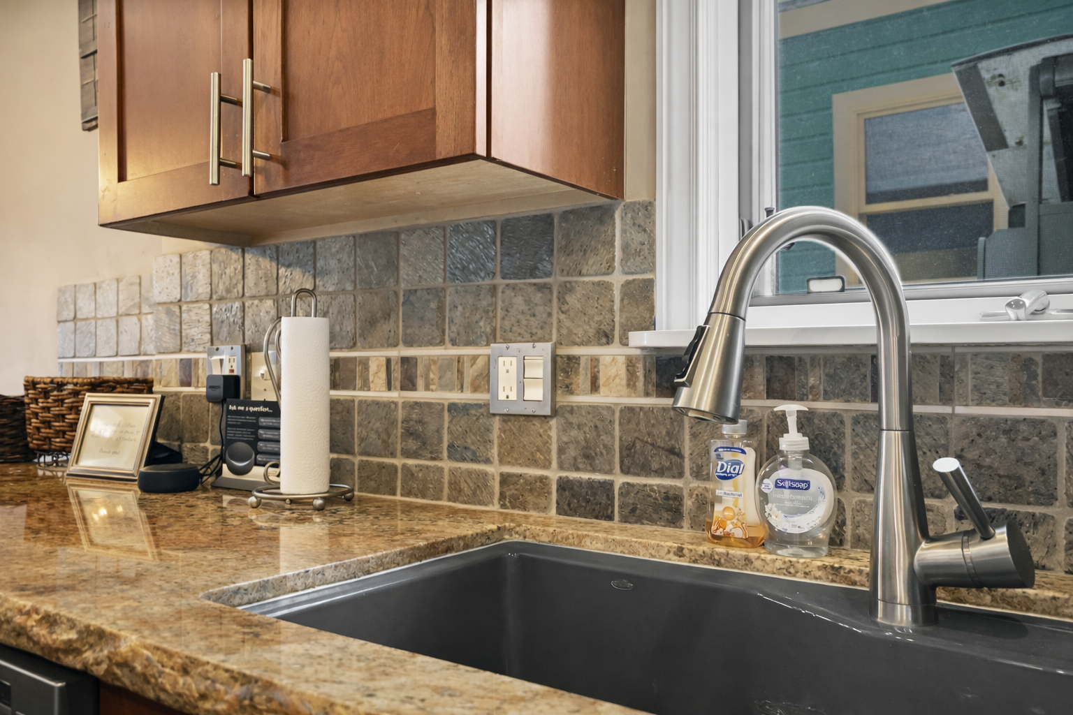 Prepare meals in our fully-equipped, modern kitchen featuring sleek granite countertops, a stylish tile backsplash, and a large sink.