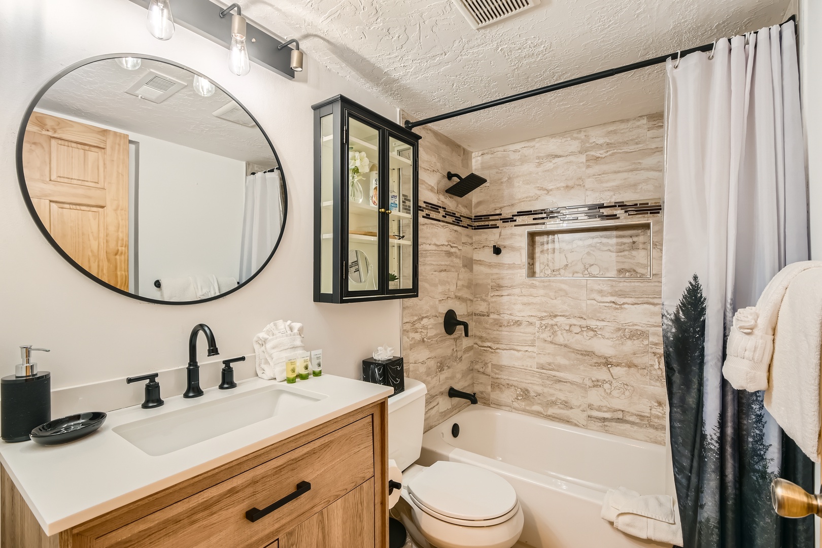 Your private bathroom combines modern style with warm wood tones, featuring a spacious tub-shower combo and thoughtful built-in storage niche for your essentials.