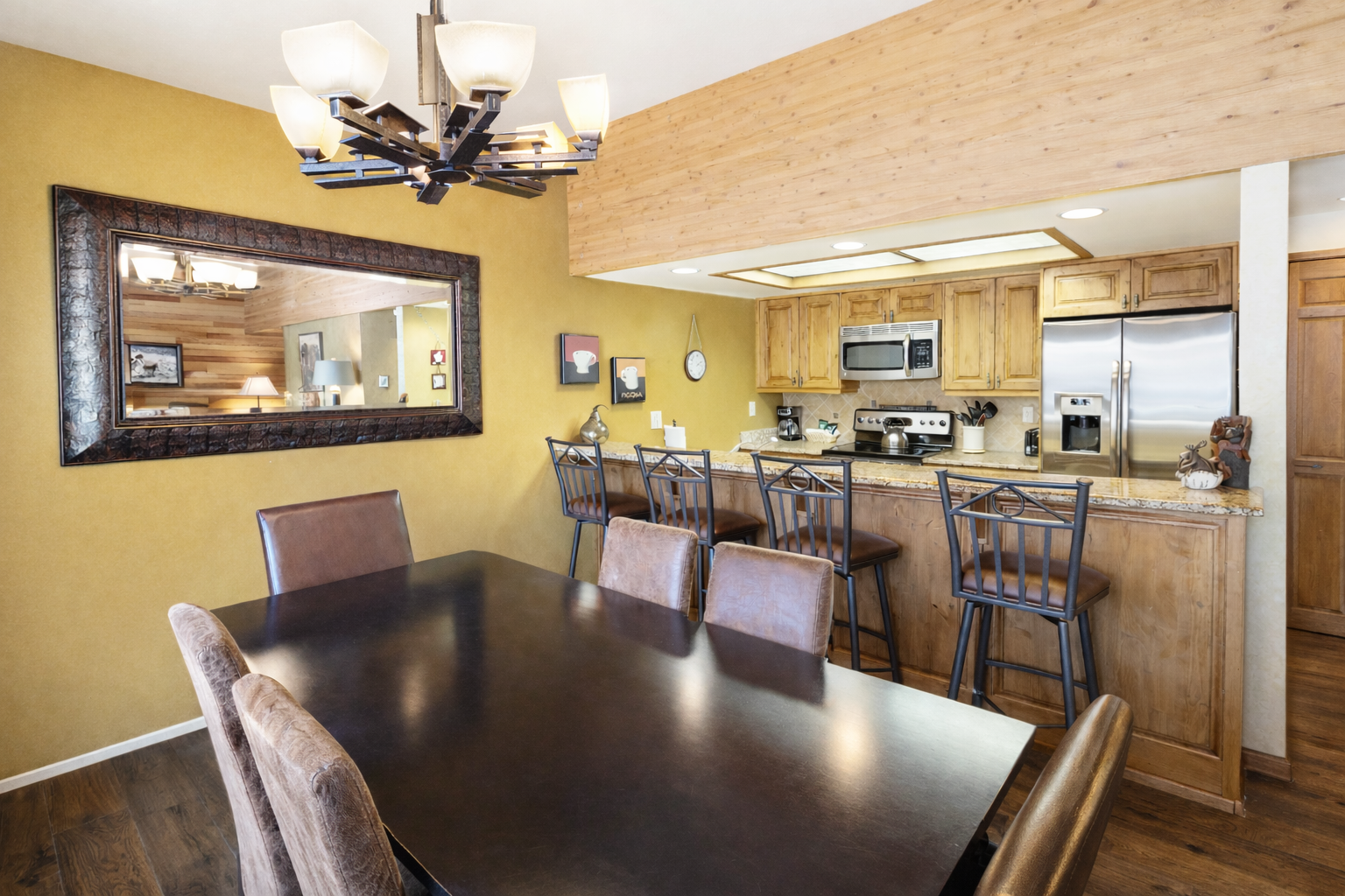 Gather around the spacious dining table where your group can share meals and stories, then step into the open kitchen featuring granite counters, stainless steel appliances, and warm wood cabinetry—everything you need to feel at home.