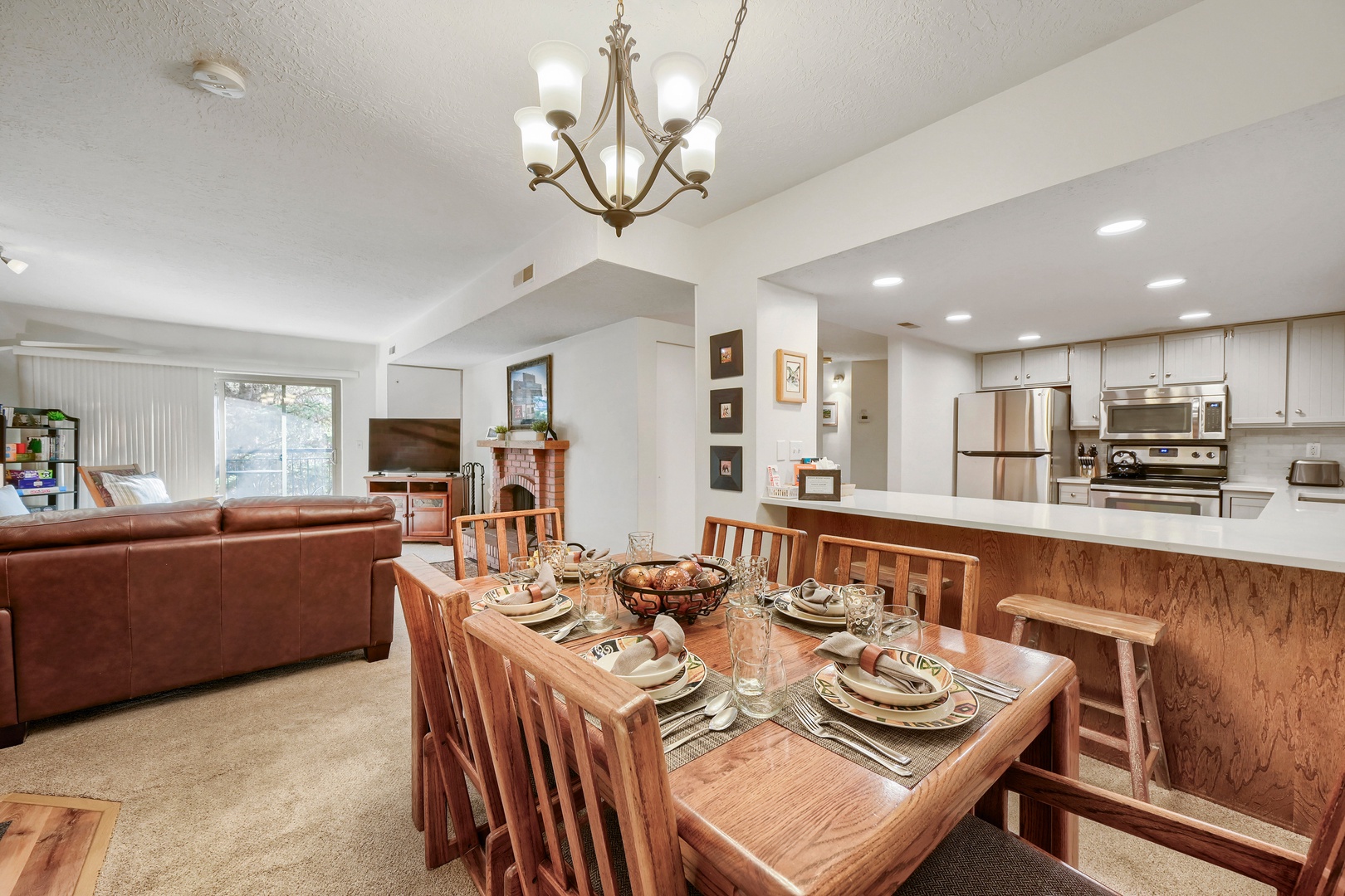 Gather around the beautifully set dining table, where your group can share meals and stories in this open-concept space. The full kitchen and cozy living area flow seamlessly together, creating the perfect setting for memorable moments.