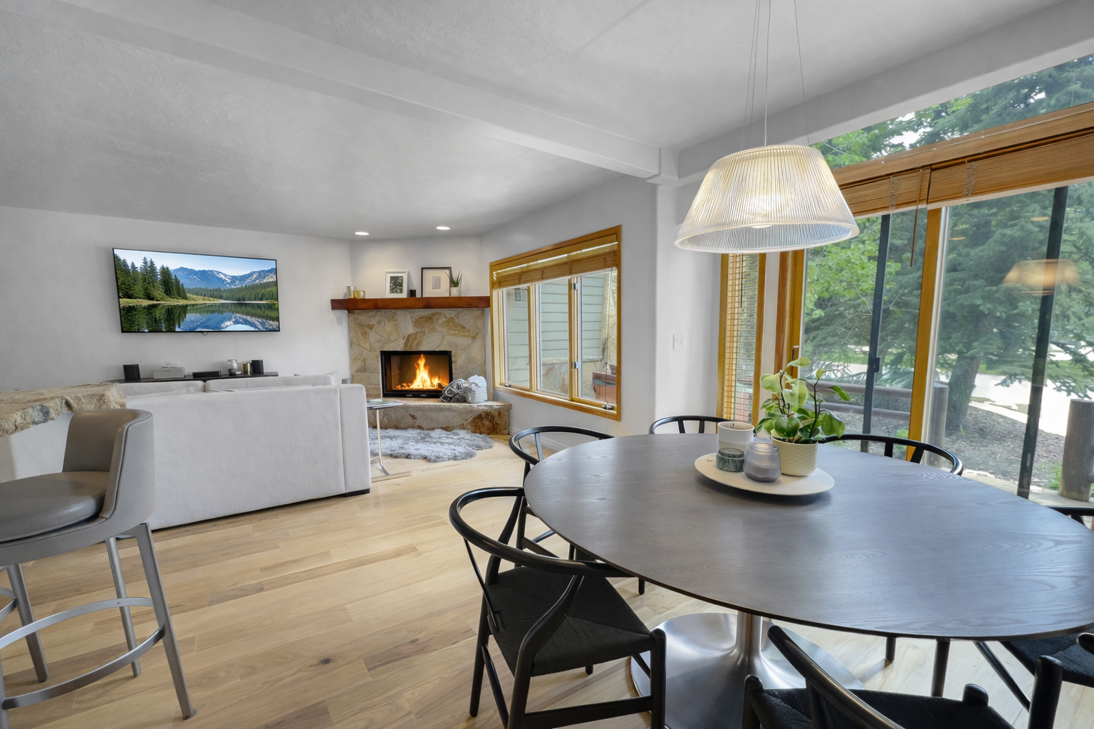 Gather around the sleek dining table while your crackling fireplace sets a cozy mood and natural light streams through windows.