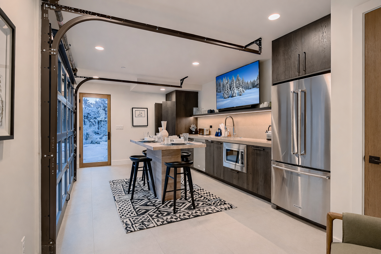 Whip up a meal or snack in this fully-equipped mother-in-law modern kitchen, featuring stainless steel appliances, a large island with seating, and even a TV for entertainment.