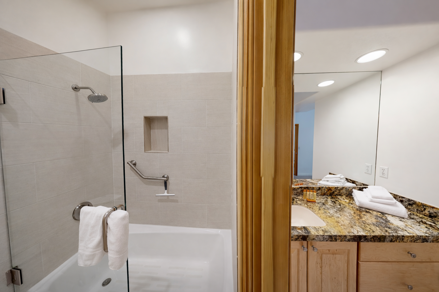 This bright, modern bathroom features a sleek double vanity with elegant stone countertops and a spacious walk-in shower, offering a refreshing start to your day.
